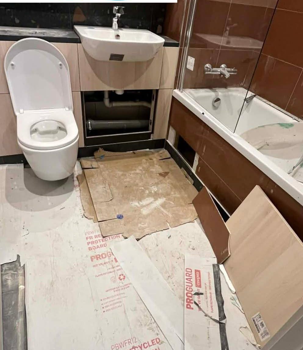 Before: New-build bathroom after the builders' clean: grey tiled floor and white sink